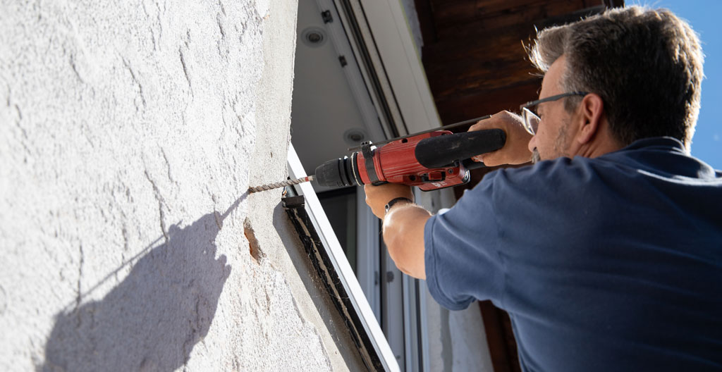 Técnico instalador señalando puntos de anclaje en pared exterior